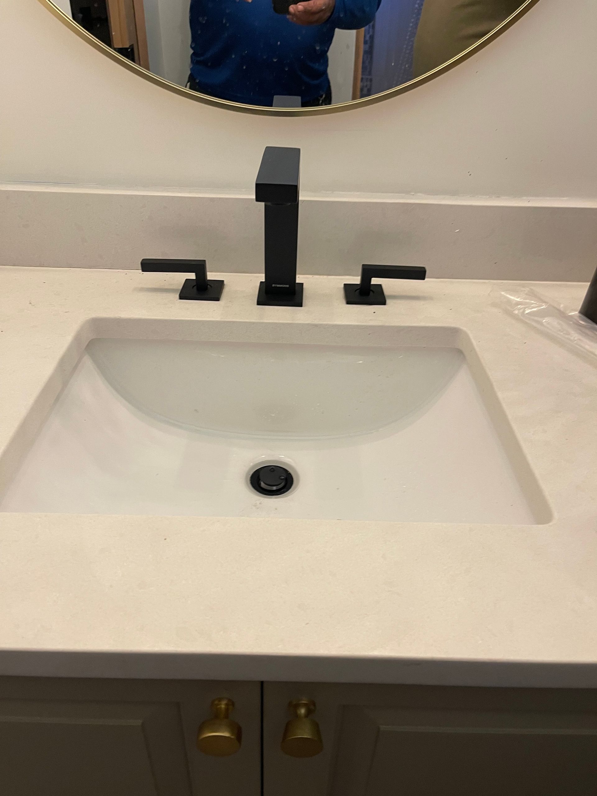 A bathroom sink with a black faucet and a mirror.