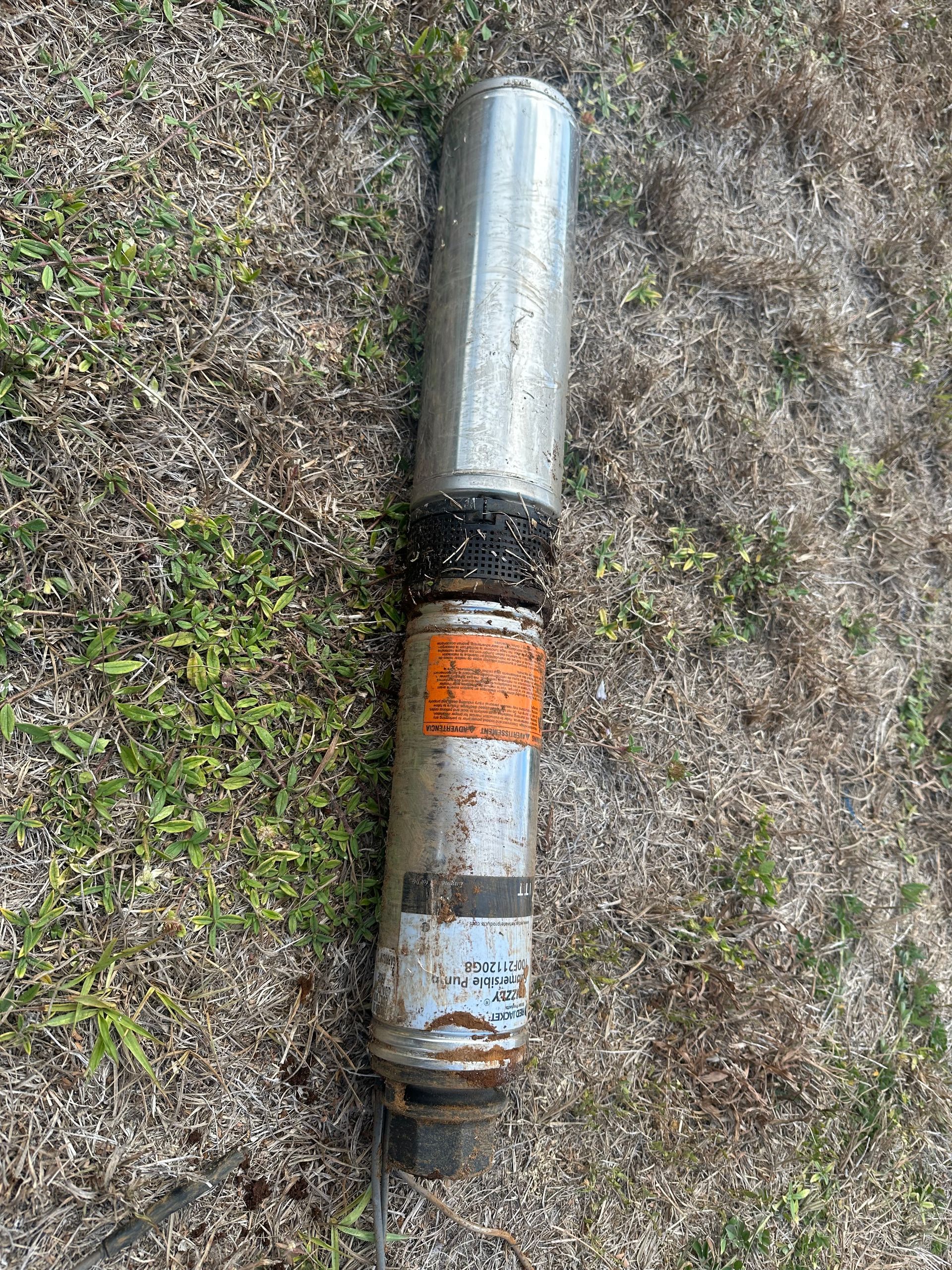 A metal pipe is sitting on top of a grass covered field.