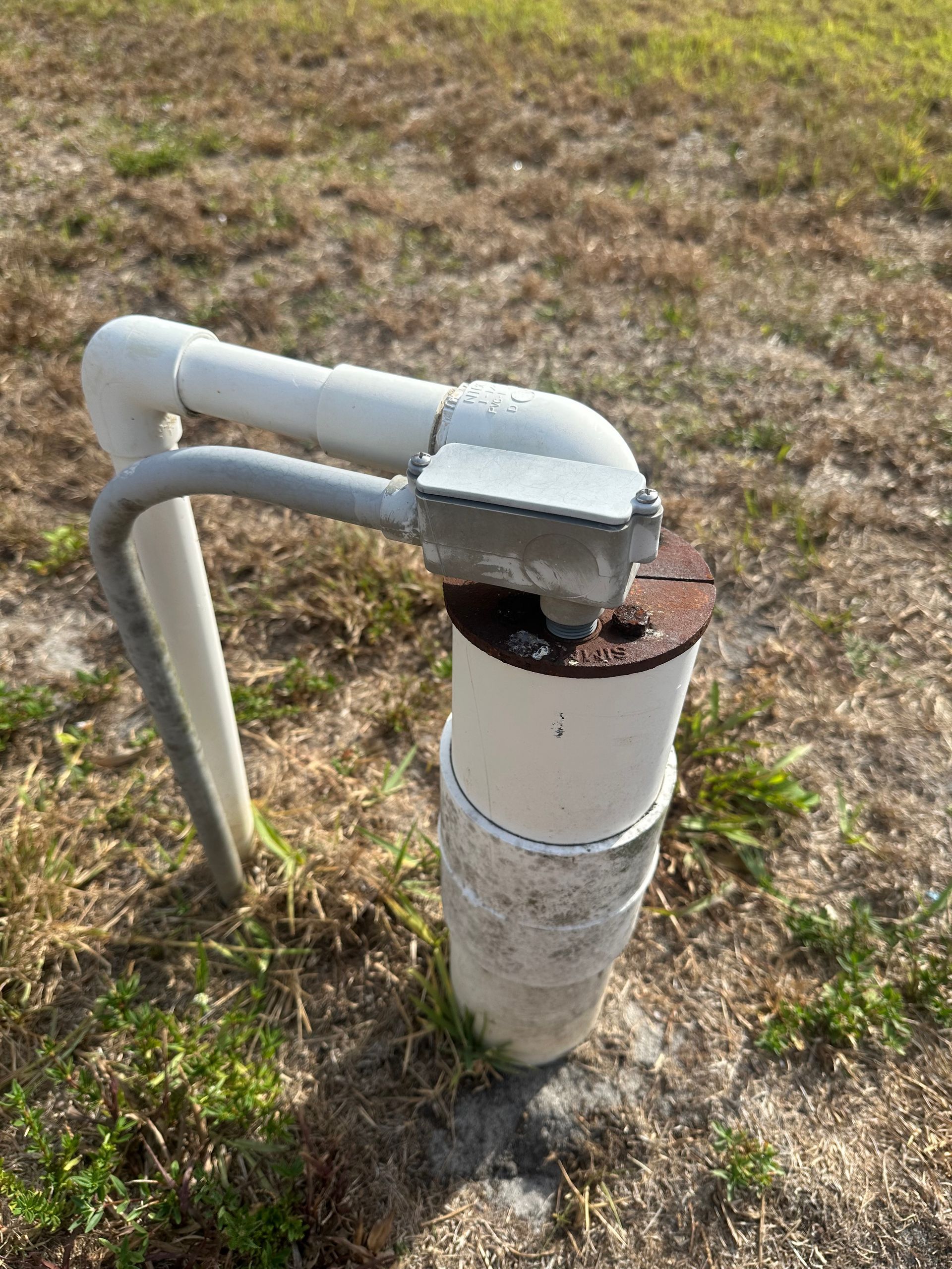 A white pipe is sitting in the middle of a field.