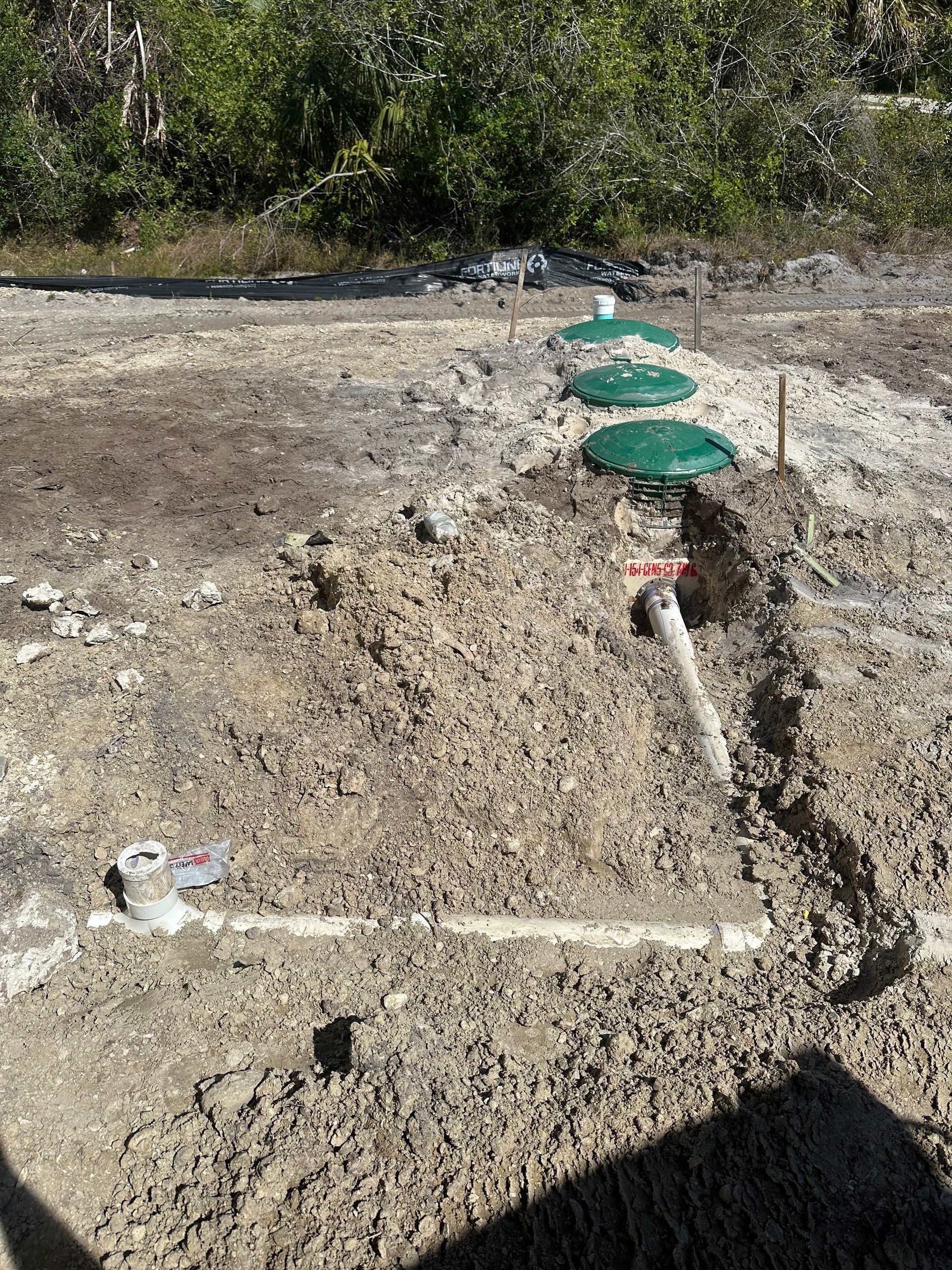 A septic system is being installed in a muddy field.
