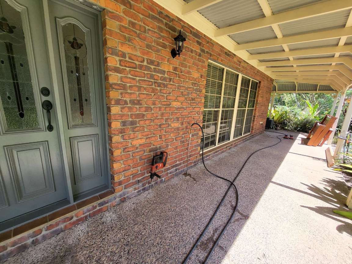 A Brick House With a Porch and a Hose in Front of It — Superior Termite & Pest Control in Bundaberg, QLD