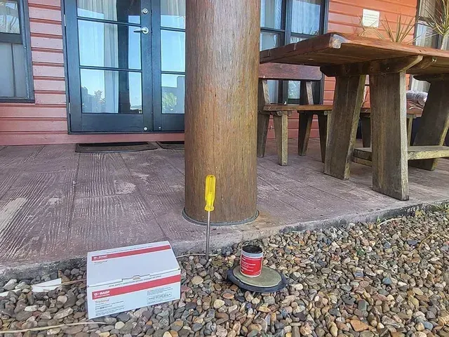 A Screwdriver is Sitting on the Ground Next to a Wooden Post — Superior Termite & Pest Control in Bundaberg, QLD