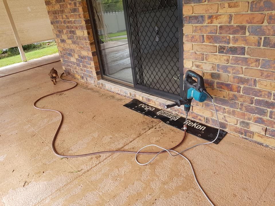 A Brick Building With a Sliding Glass Door and a Hose Attached to It — Superior Termite & Pest Control in Bundaberg, QLD