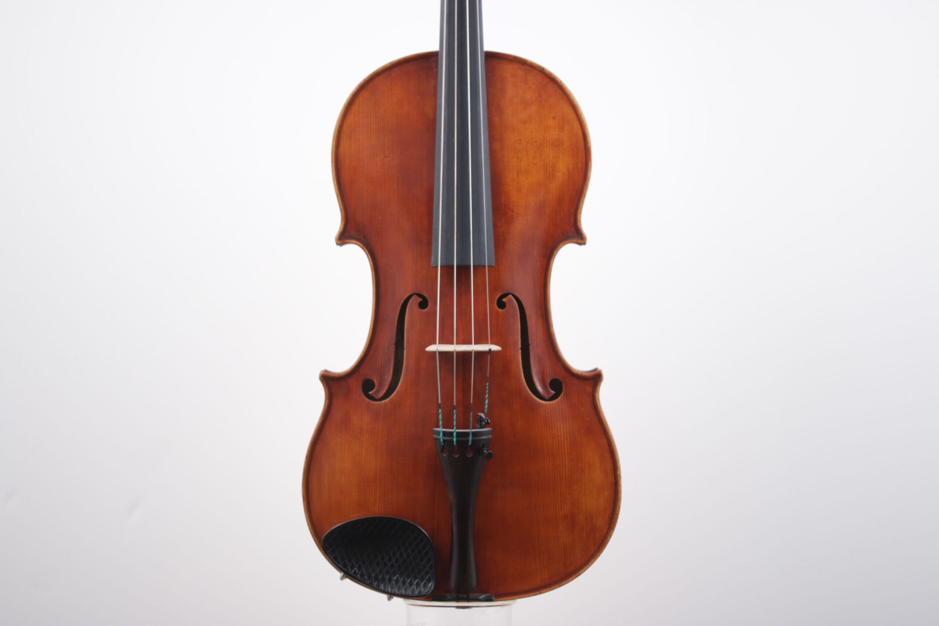 A violin is sitting on a white surface.