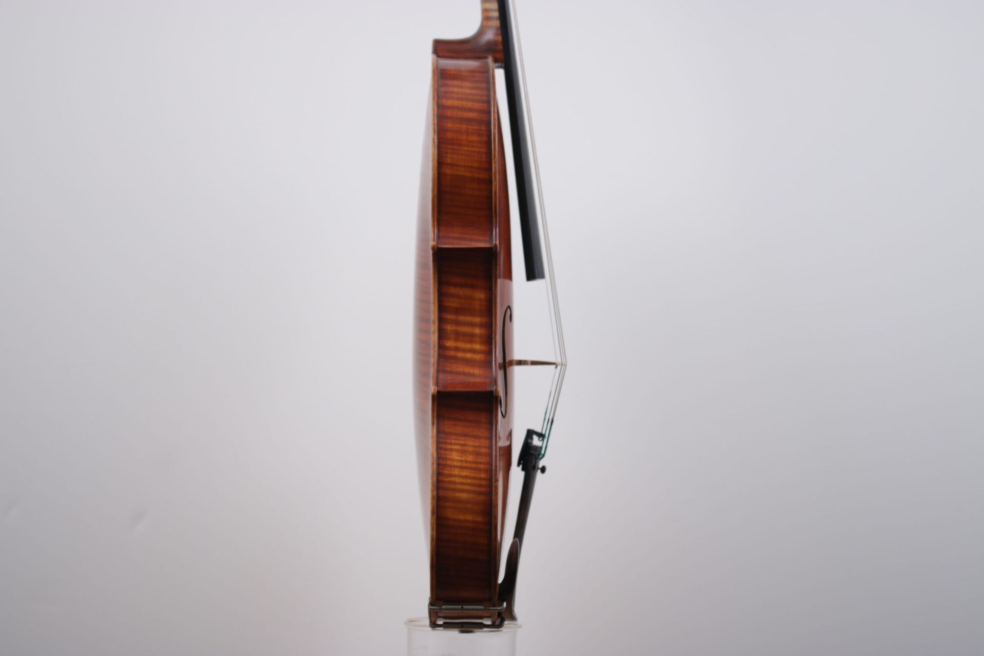 A violin with a bow is sitting on a white surface.