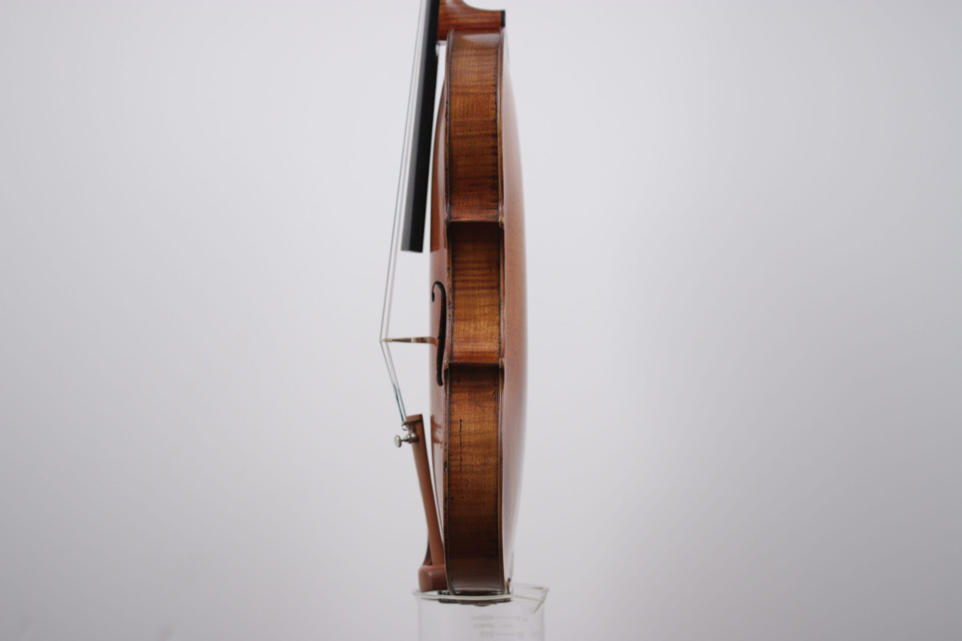 A violin is sitting on top of a glass on a white background.