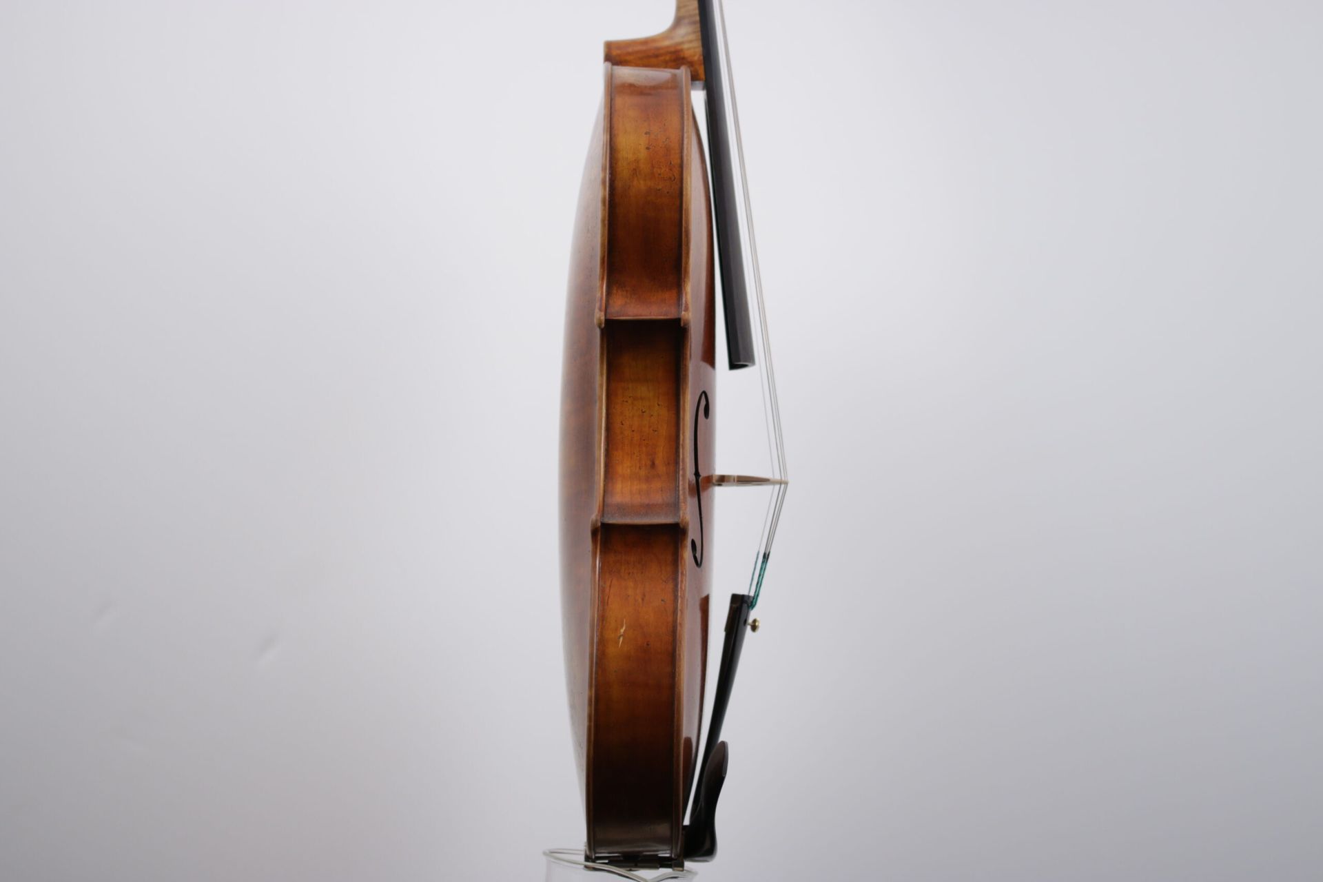 A violin with a bow is sitting on a white surface.