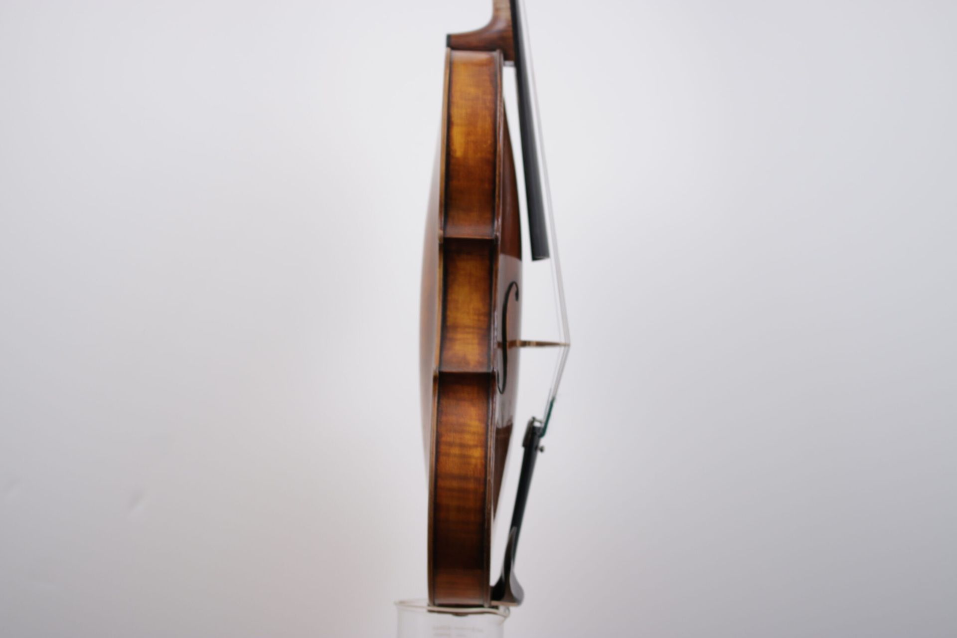 A violin with a bow is sitting on a white surface.