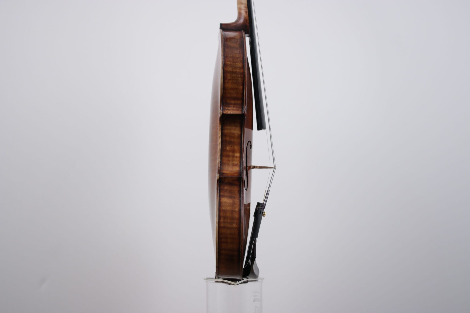 A violin is sitting on top of a glass on a white background.