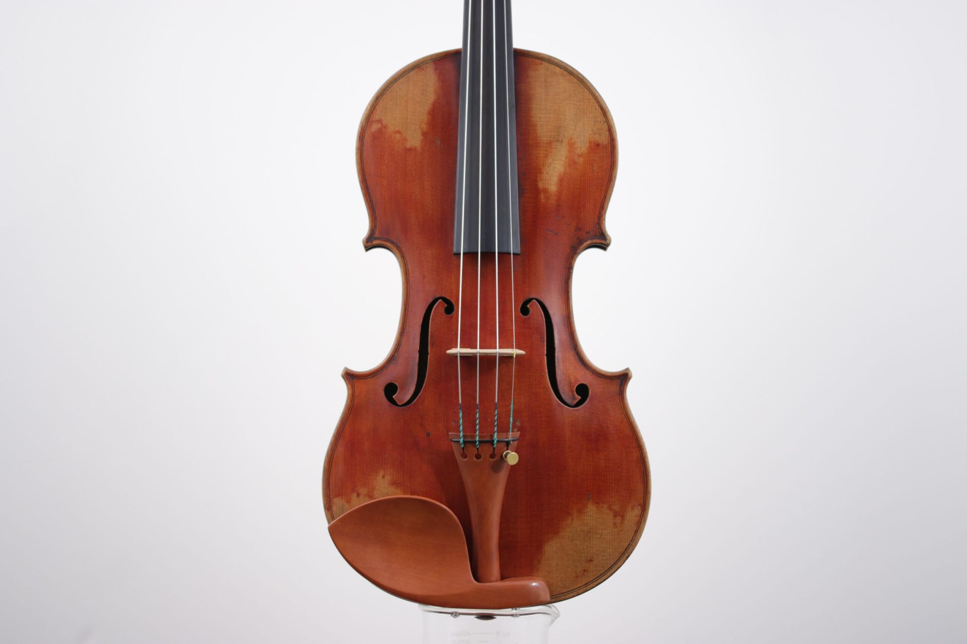 A violin is sitting on a white surface.