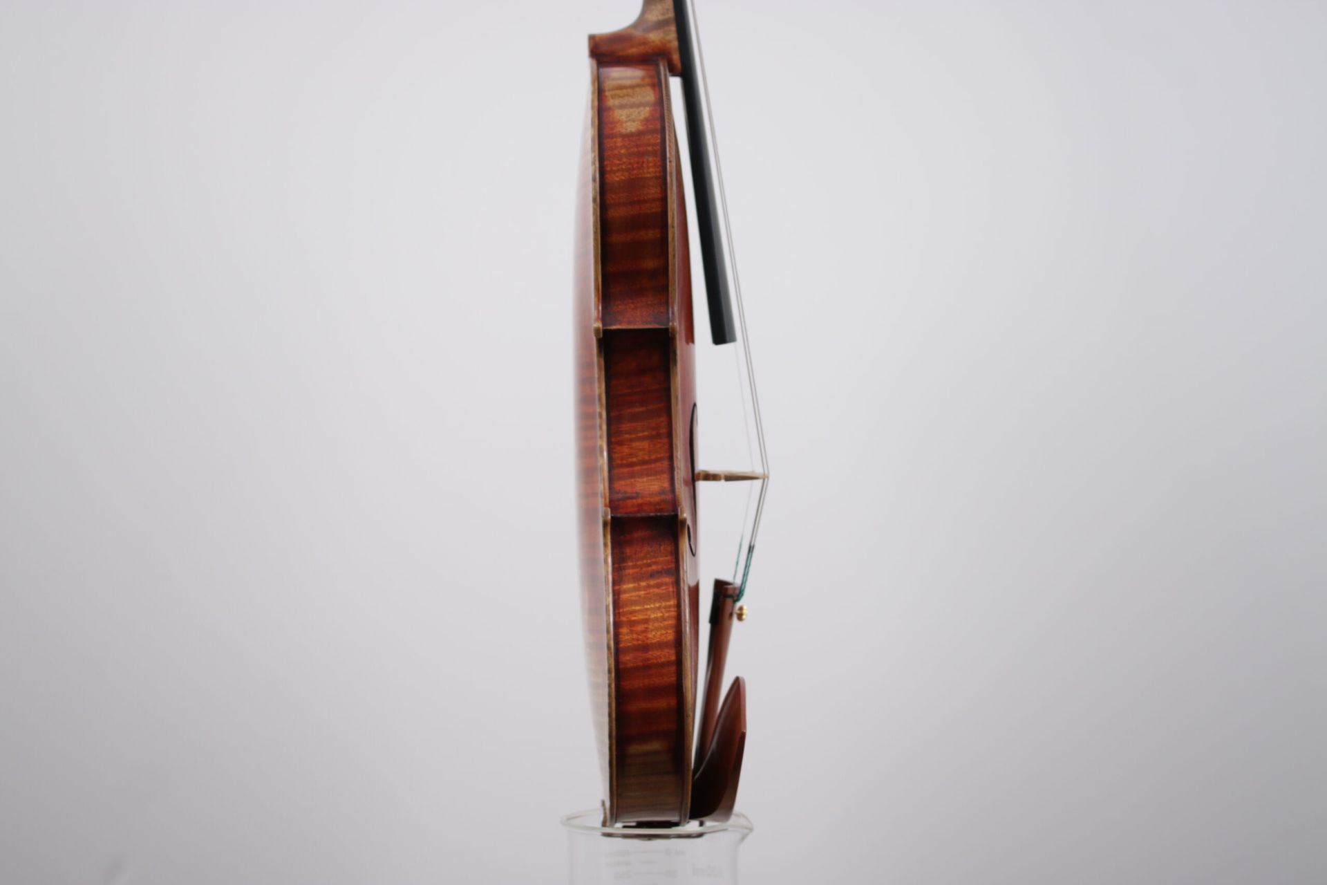 A violin with a bow is sitting on a white surface.