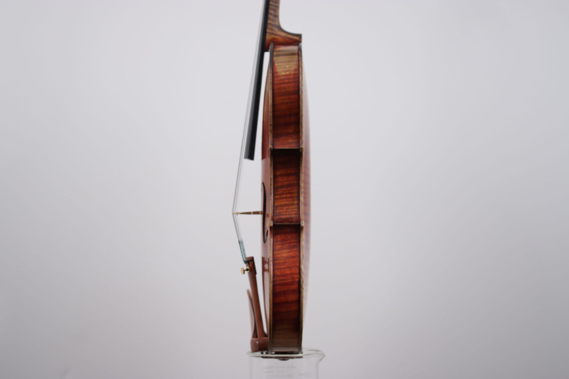 A violin with a bow is sitting on a white surface.