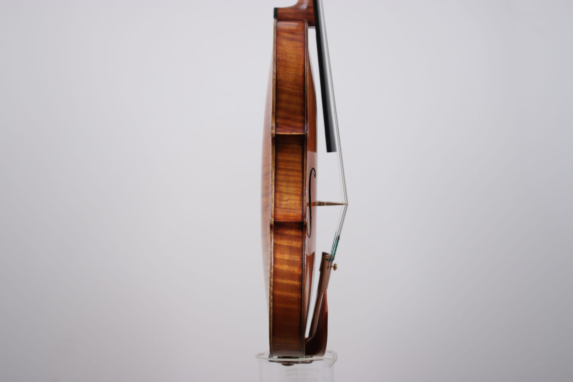 A violin is sitting on top of a glass on a white background.