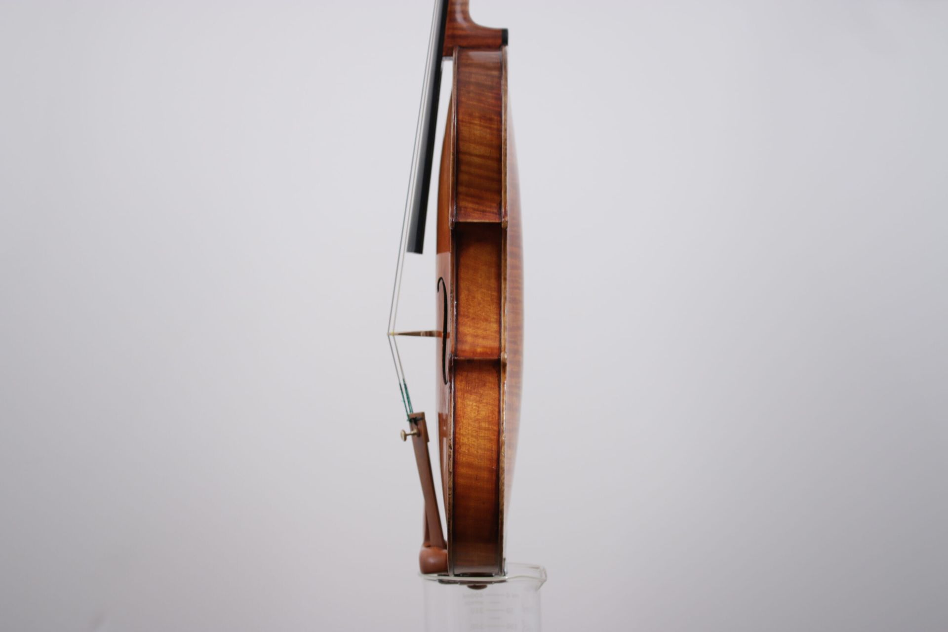 A violin is sitting on top of a glass on a white background.