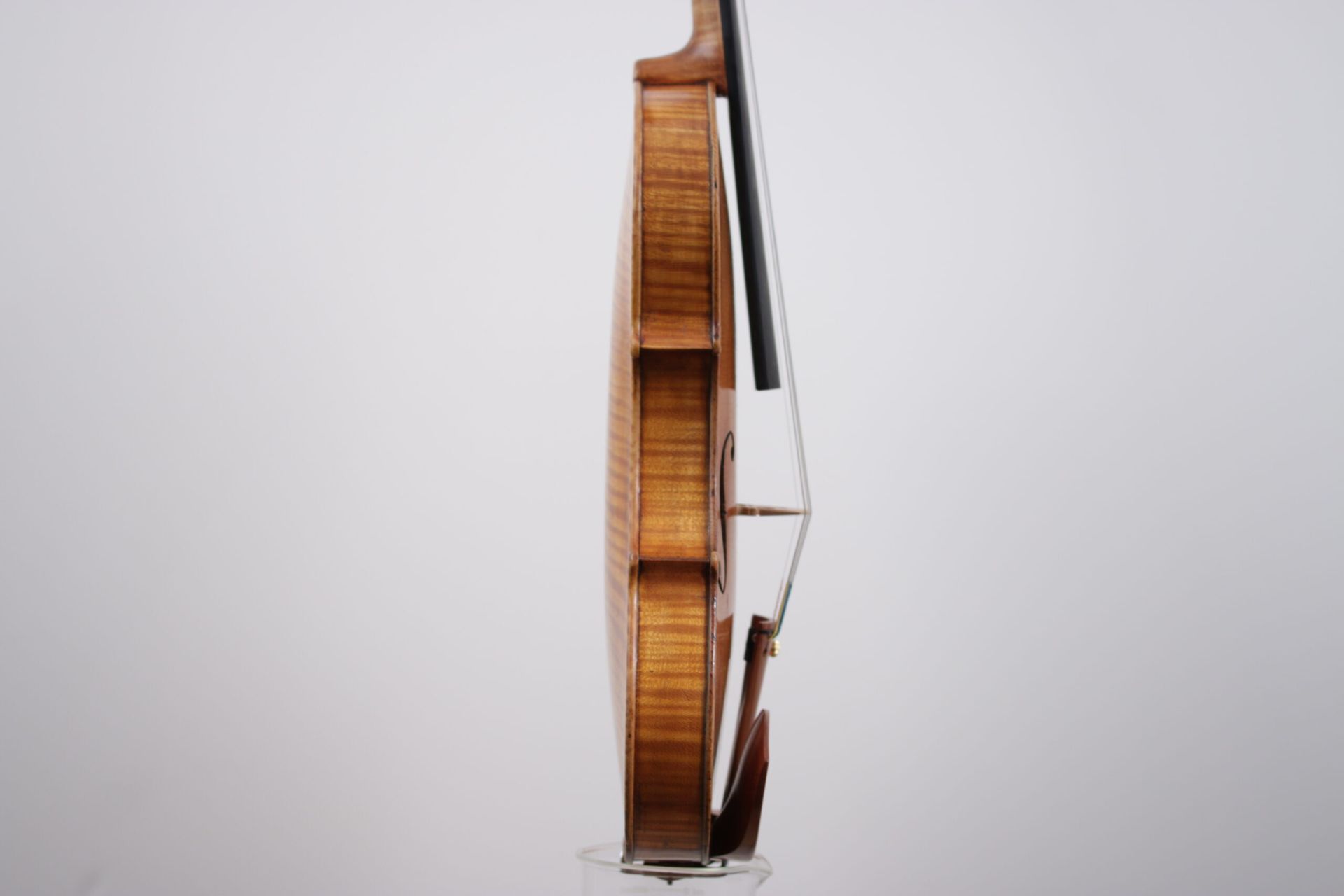 A violin with a bow is sitting on a white surface.