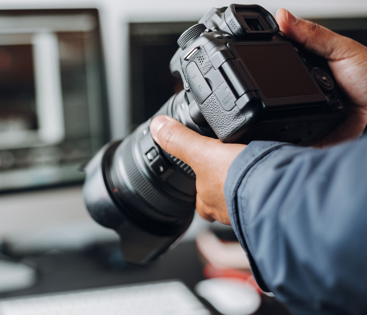 A person is holding a camera in front of a computer screen