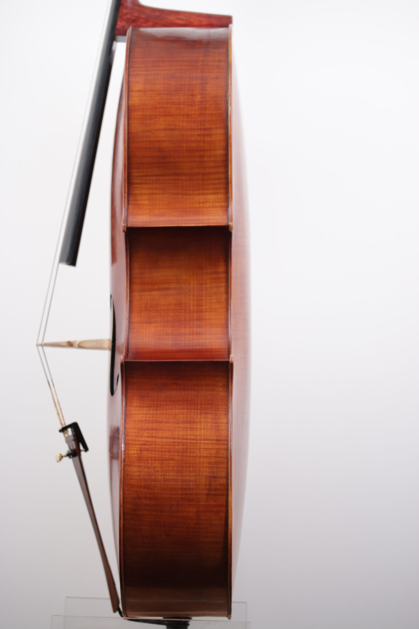 A cello with a bow is sitting on a white surface.