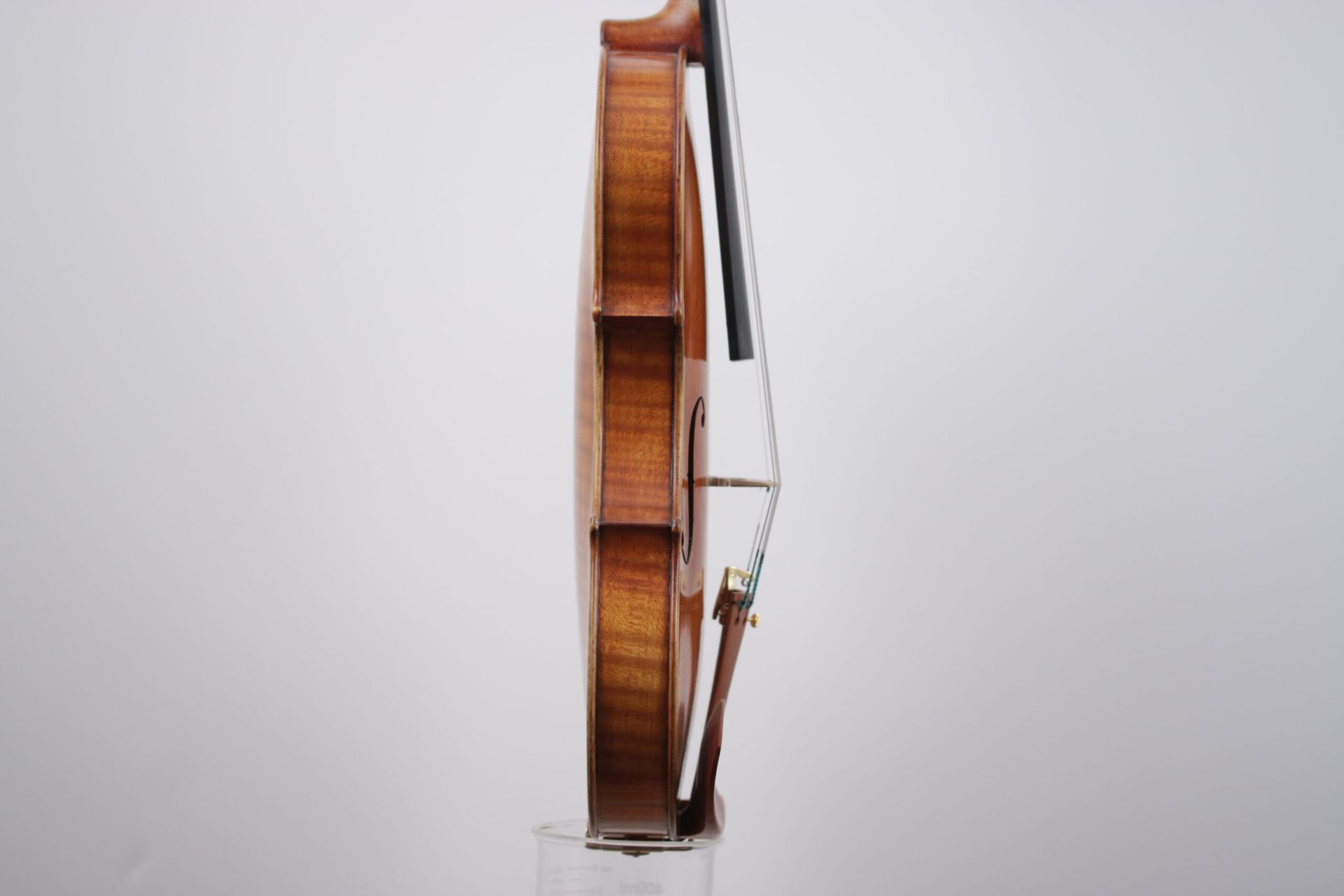 A violin with a bow is sitting on a white surface.