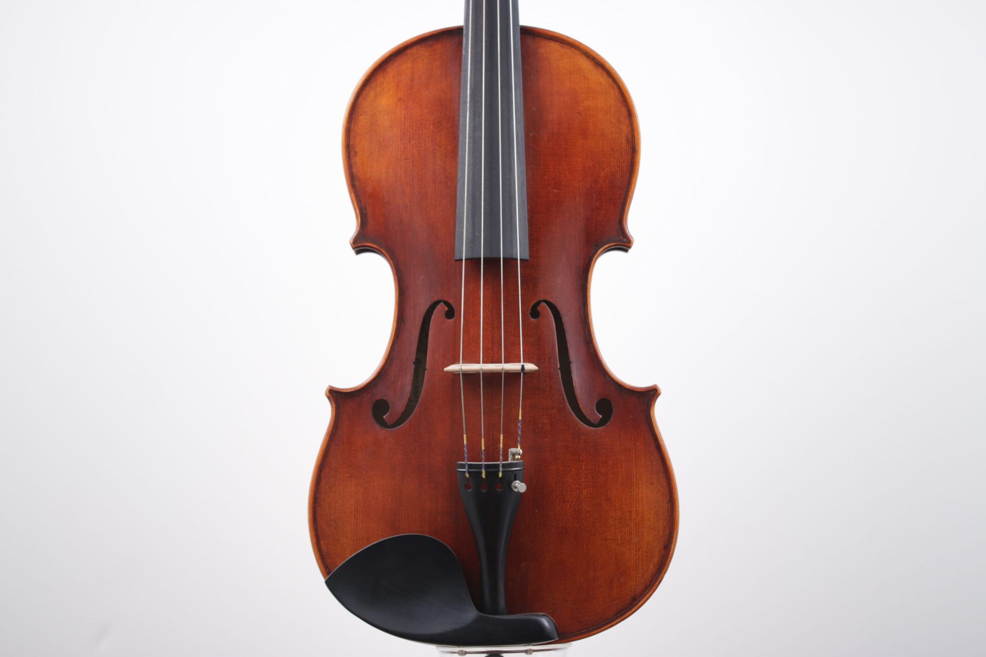 A violin is sitting on a stand on a white background