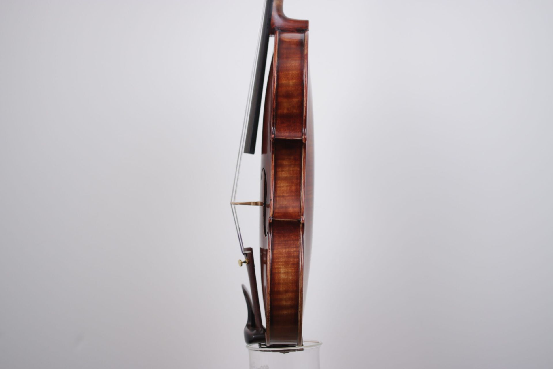 A violin is sitting on top of a glass on a white background.