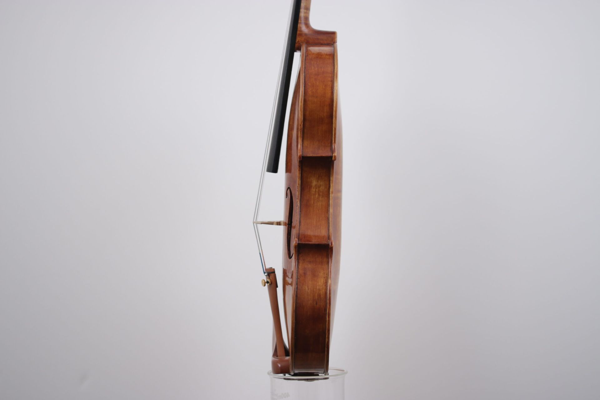 A violin is sitting on top of a glass on a white background.