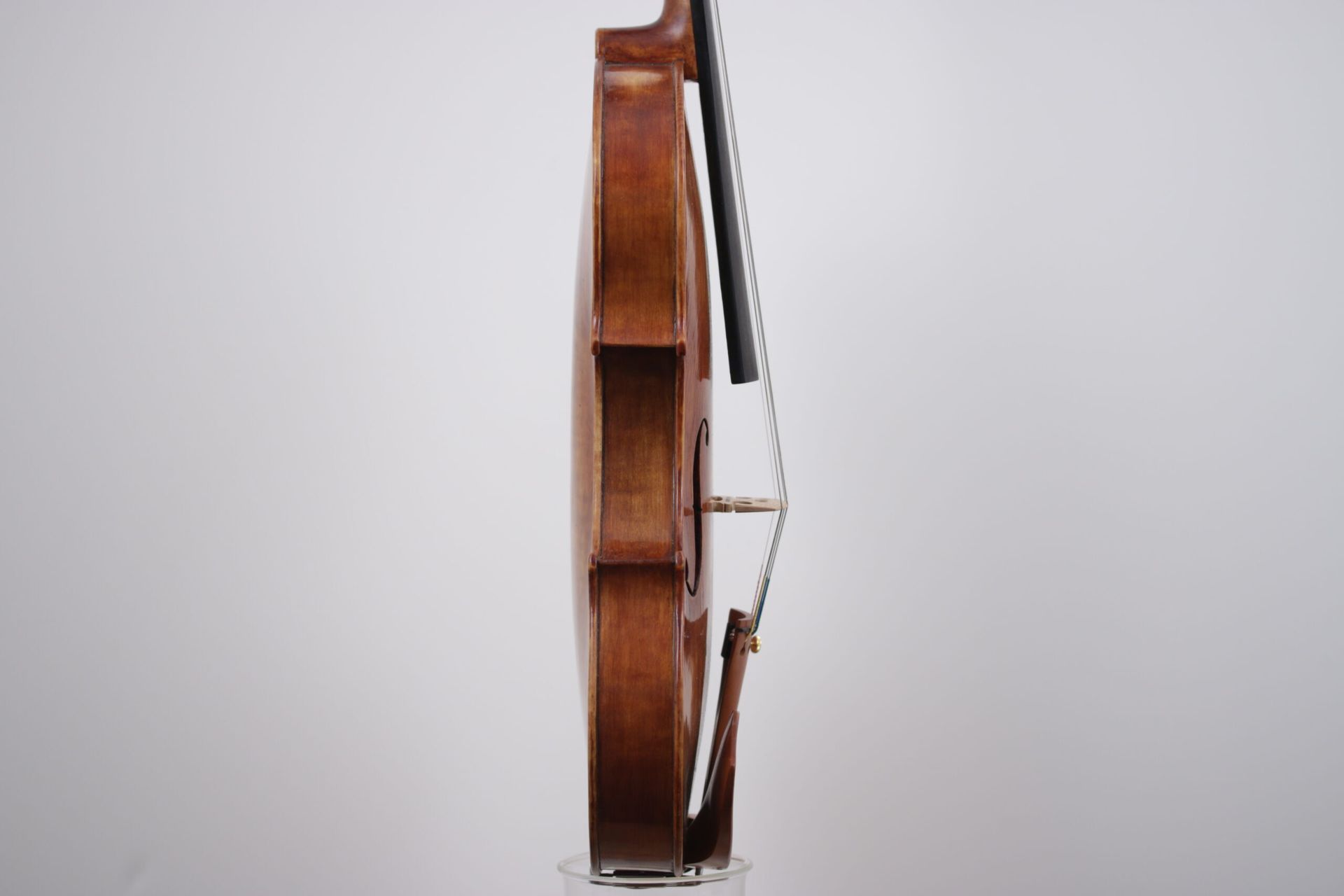 A violin is sitting on a stand on a white background.