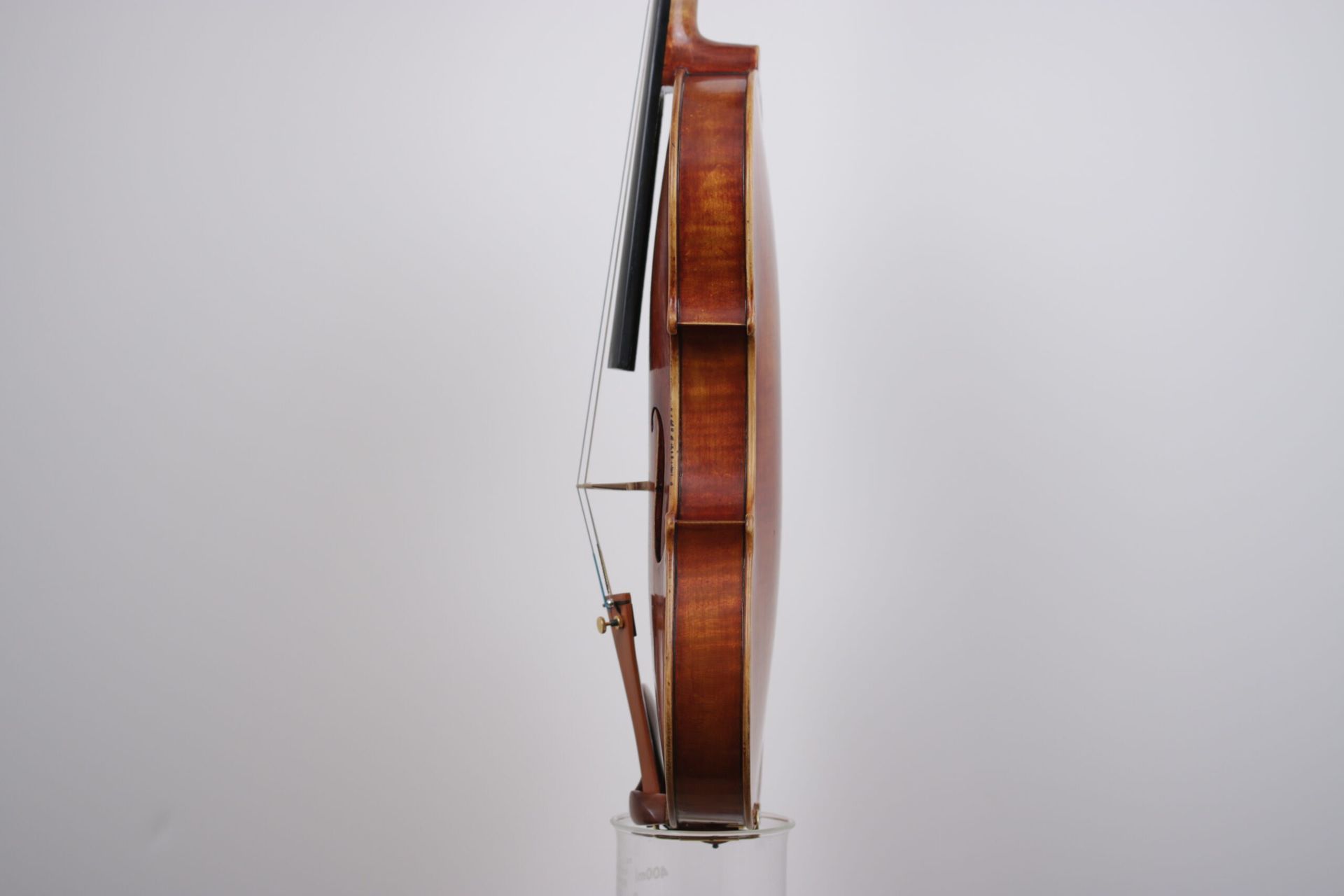 A violin is sitting on top of a glass on a white background.