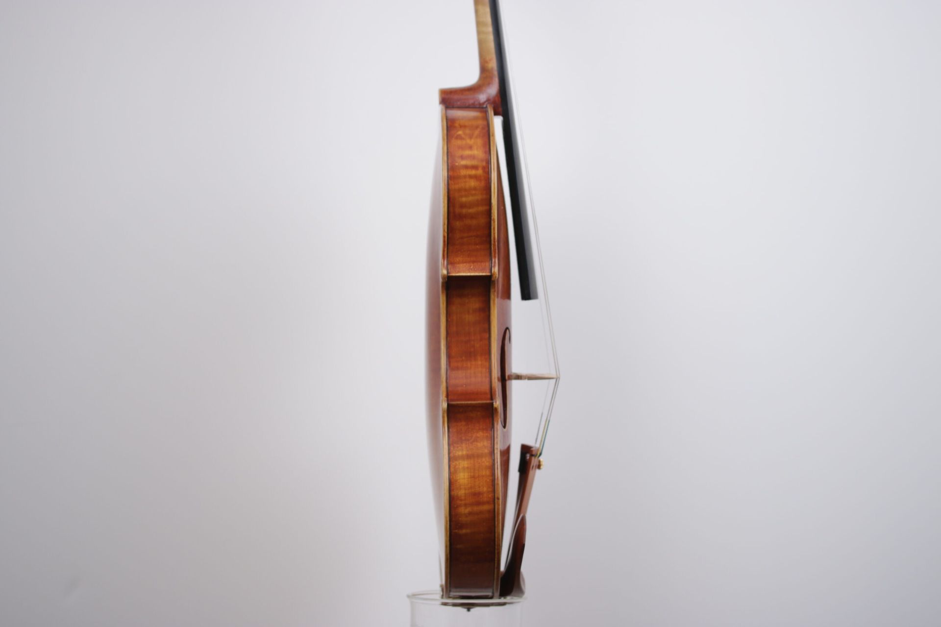 A violin is sitting on a stand on a white background.