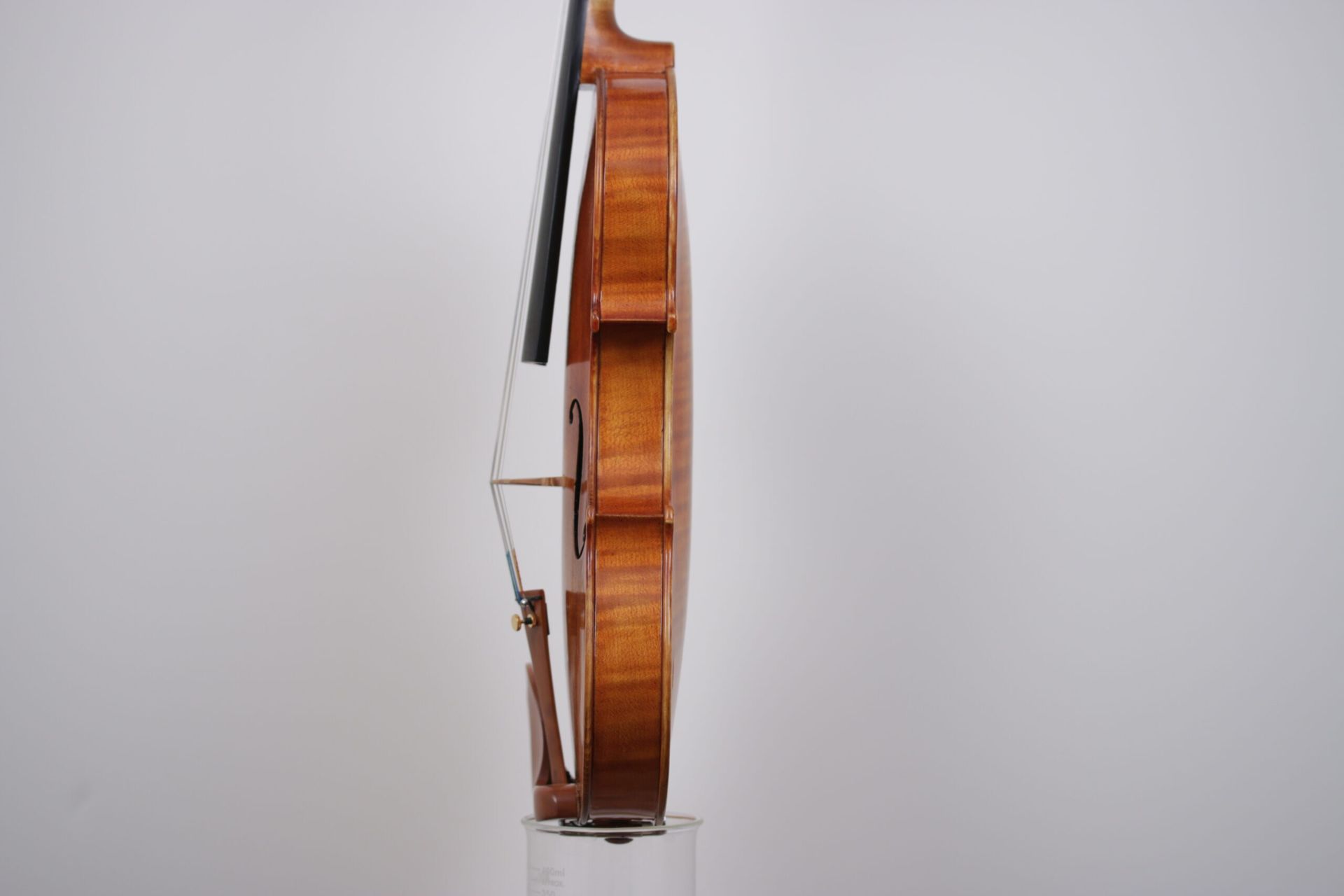A violin is sitting on top of a glass on a white background.