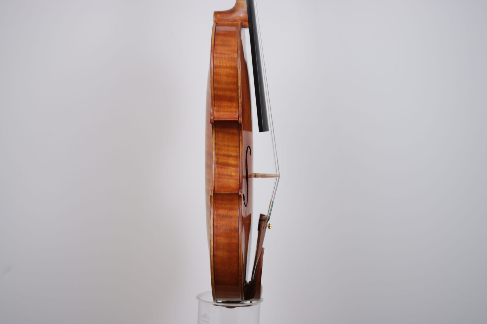 A violin is sitting on top of a glass on a white background.