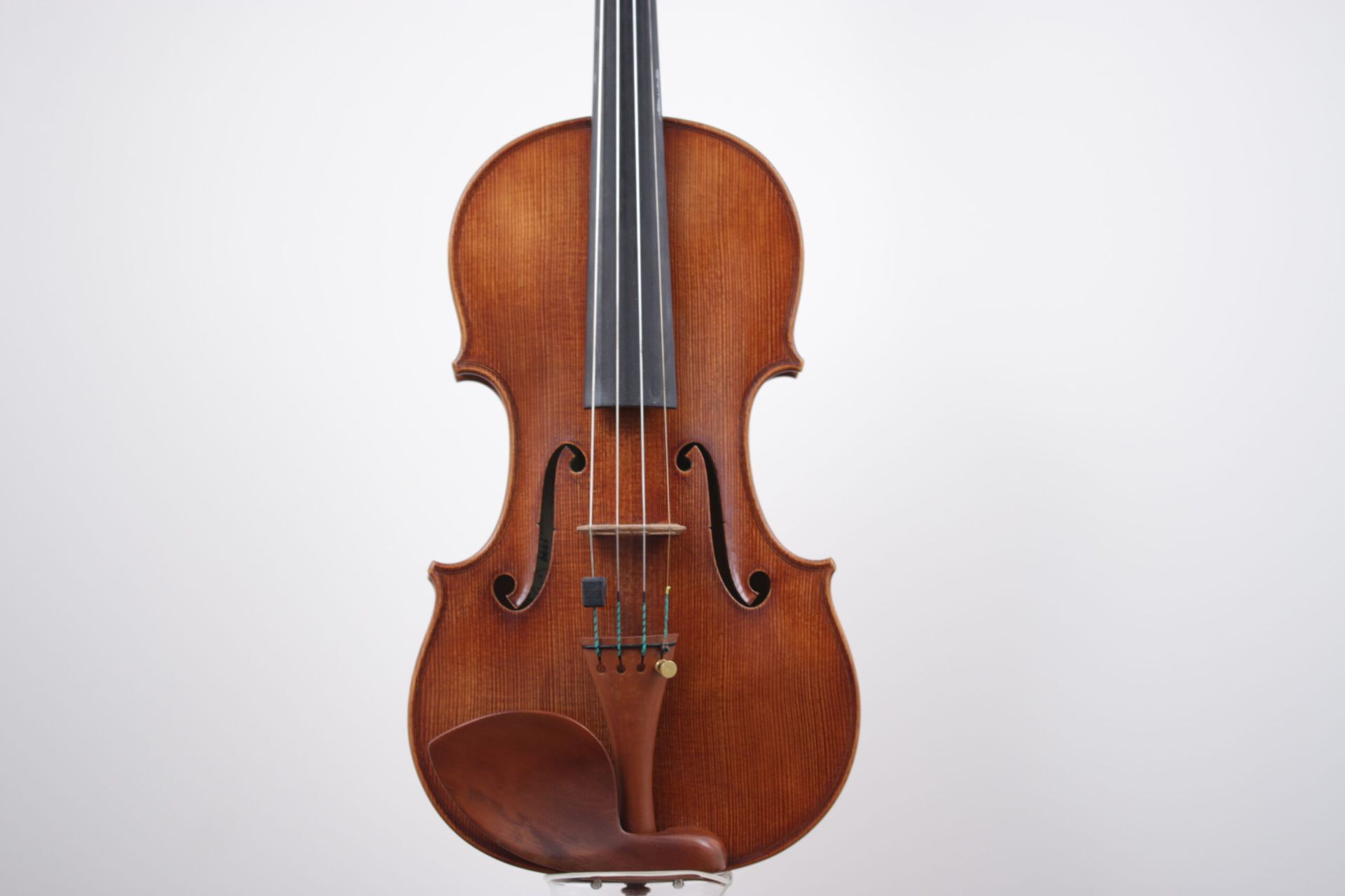 A violin is sitting on a stand on a white background.