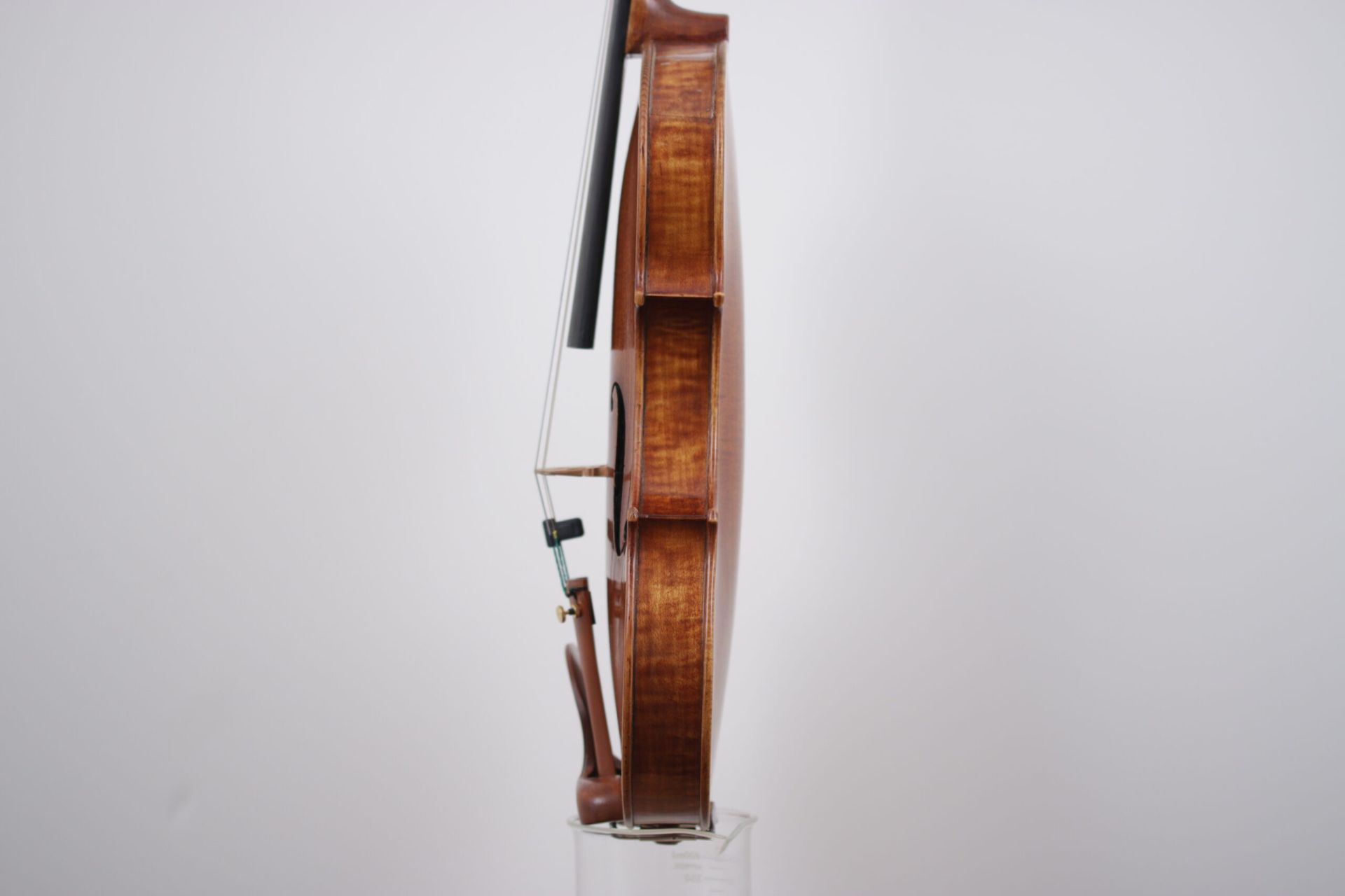 A violin is sitting on top of a glass on a white background.