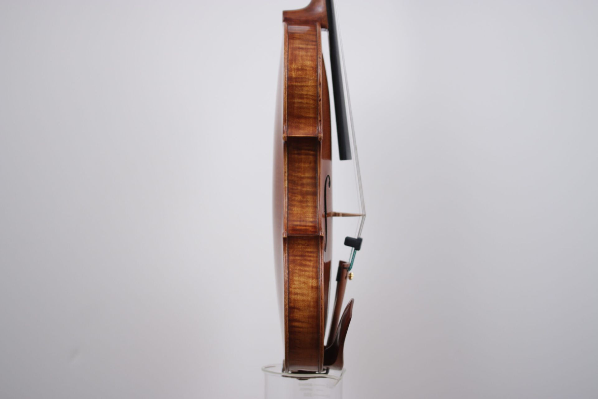 A violin with a bow is sitting on a white surface.