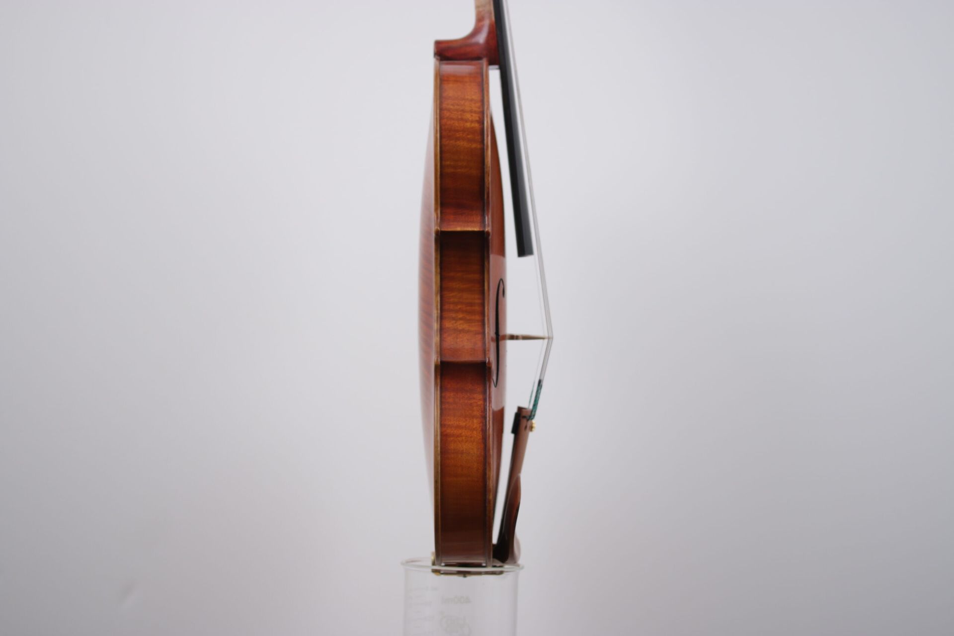 A violin is sitting on top of a glass on a white background.