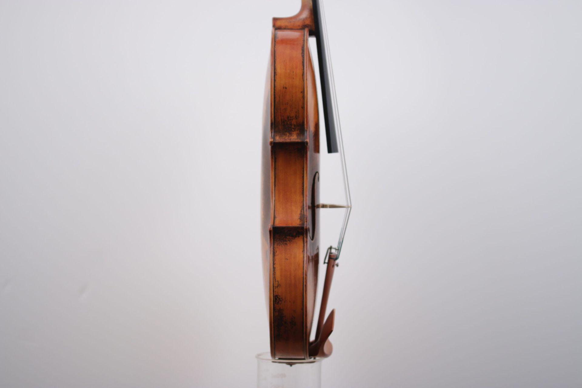 A violin is sitting on top of a glass on a white background.