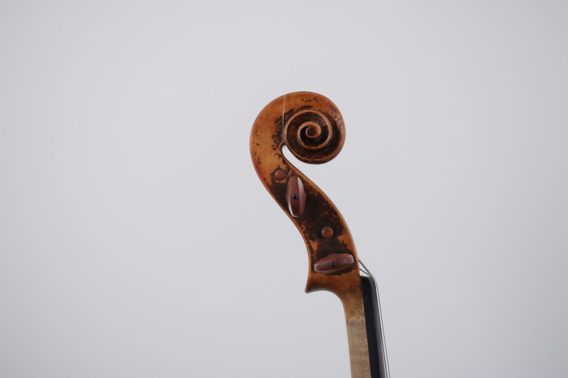 A violin is sitting on top of a glass on a white background.