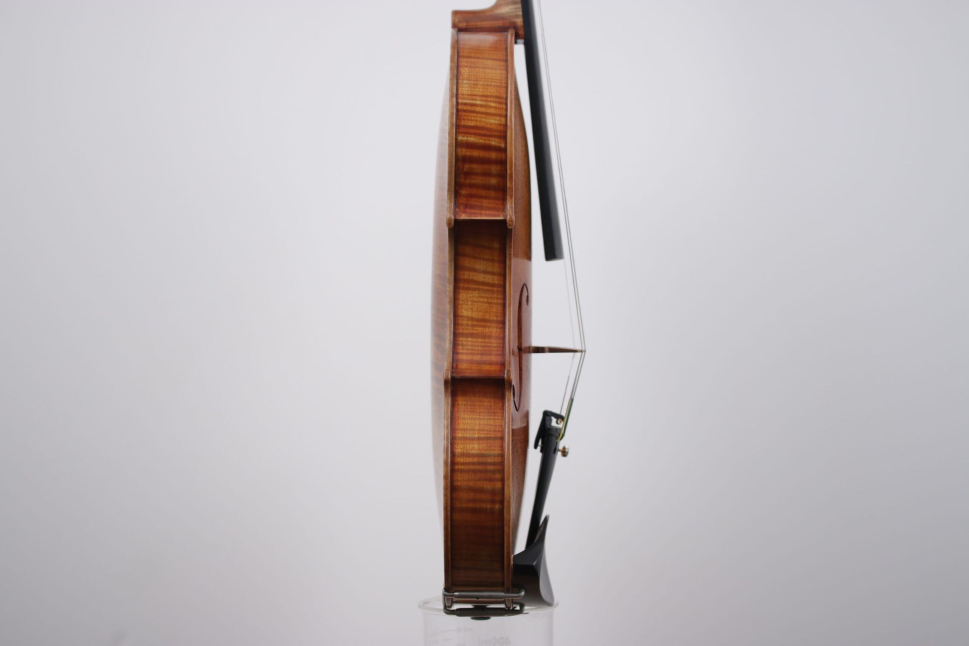 A violin with a bow is sitting on a white surface.