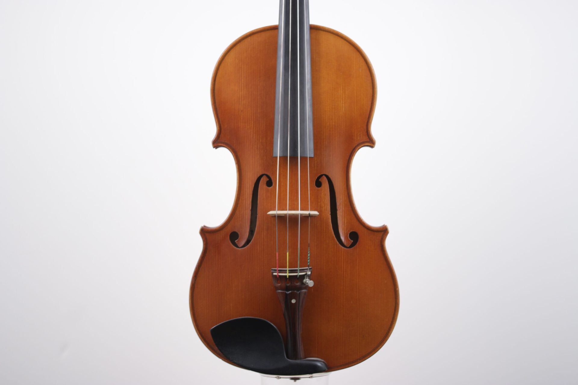 A violin with a black bow is sitting on a white surface