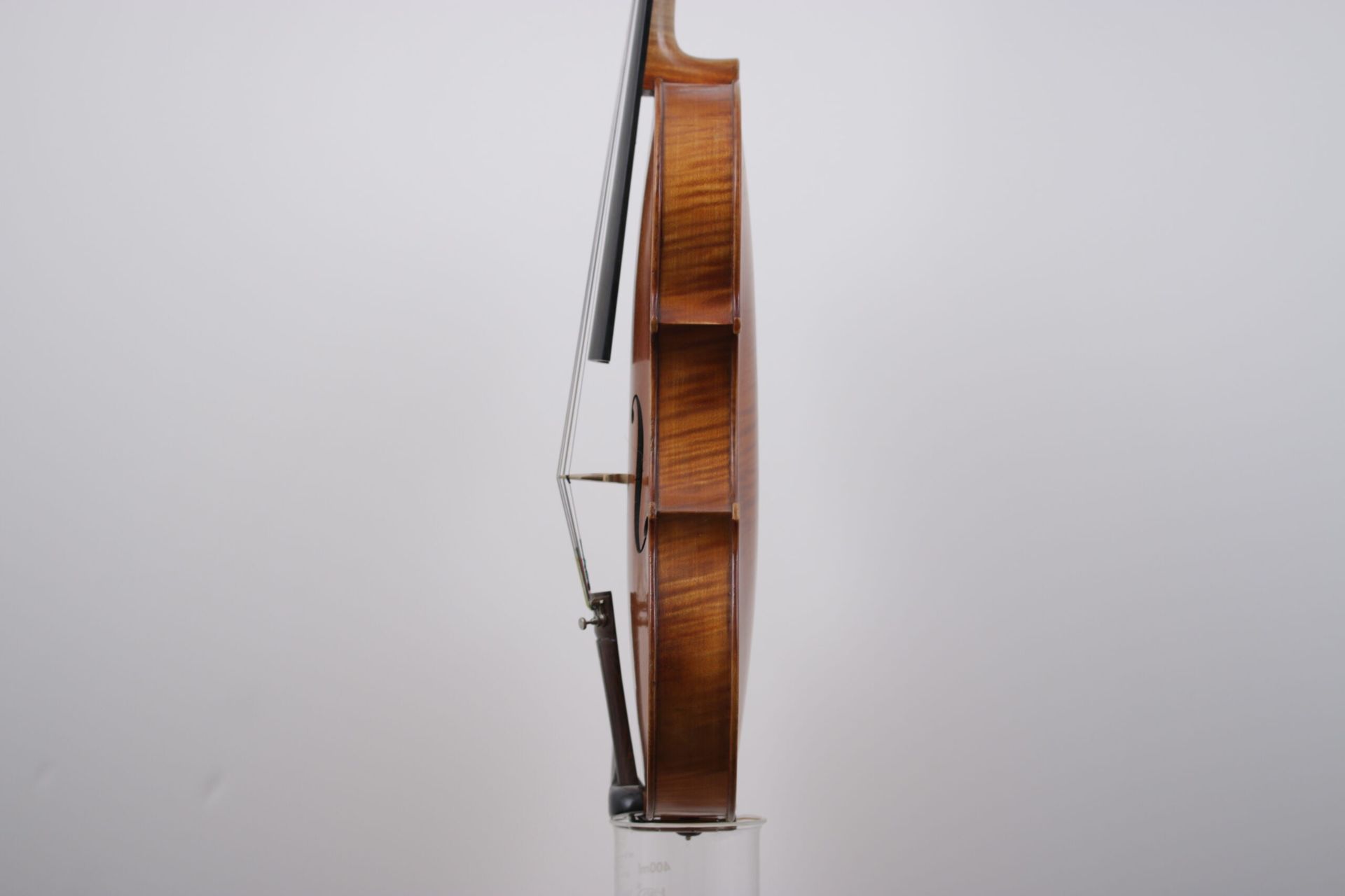 A violin is sitting on a glass against a white wall.