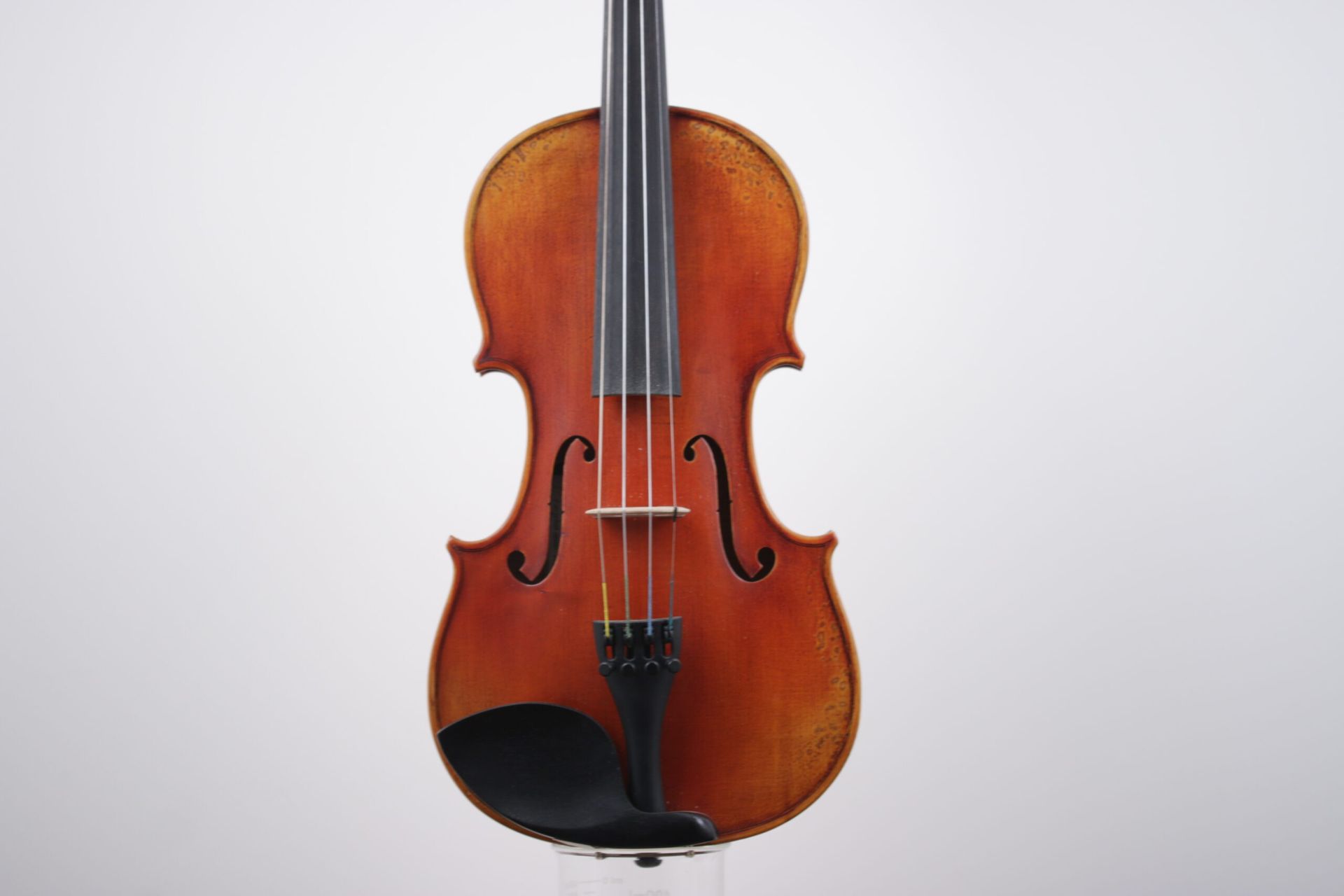 A violin is sitting on a white surface.