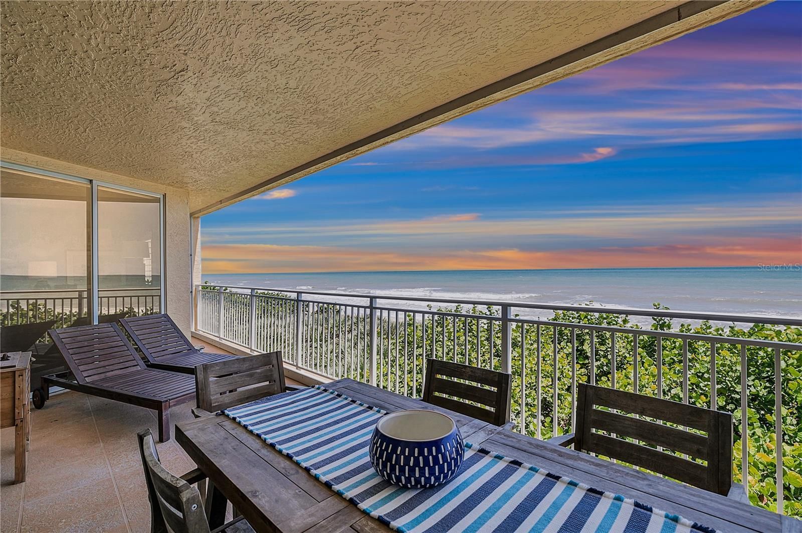 A balcony with a table and chairs overlooking the ocean