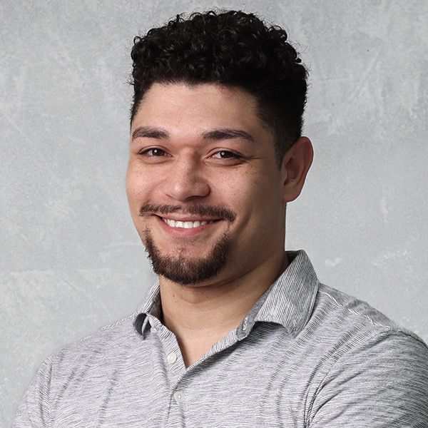 A man with curly hair and a beard is smiling for the camera.