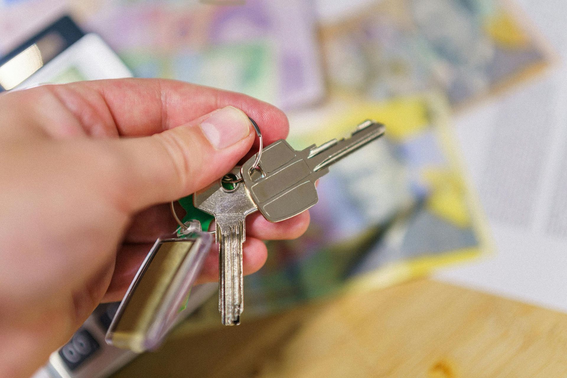 Hand holding house keys with money in the blurred background.