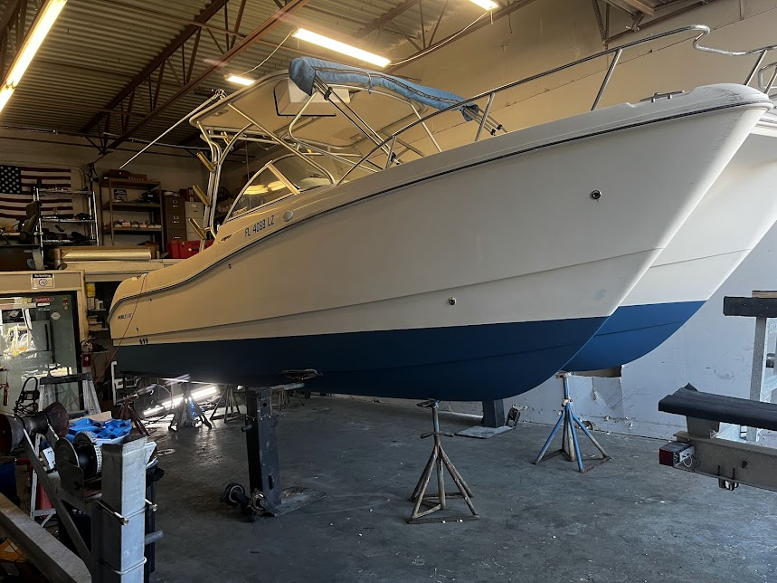White and blue catamaran boat on stands in a workshop.