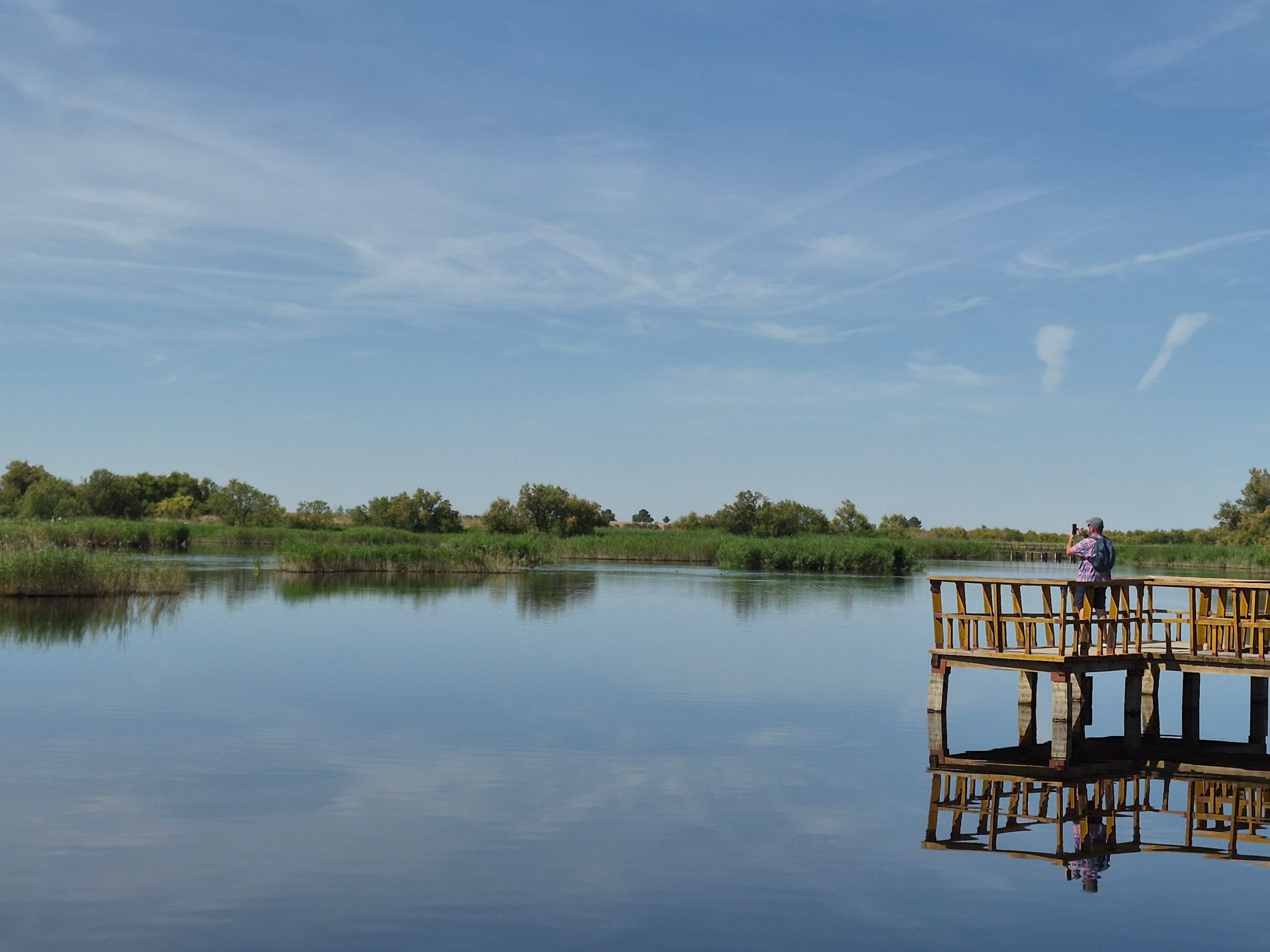 foto van water met een houten brug waarop een man staat, tablas de daimiel in daimiel