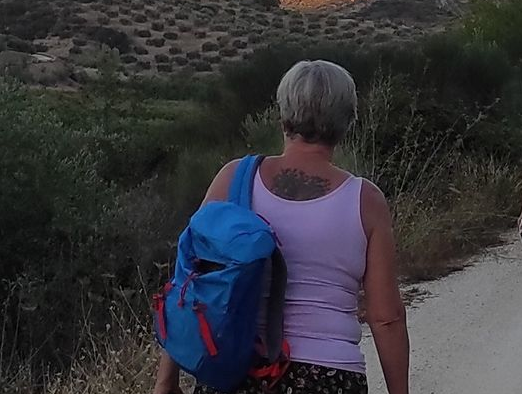 vrouw van middelbare leeftijd loopt met een blauwe rugzak door de natuur van Spanje