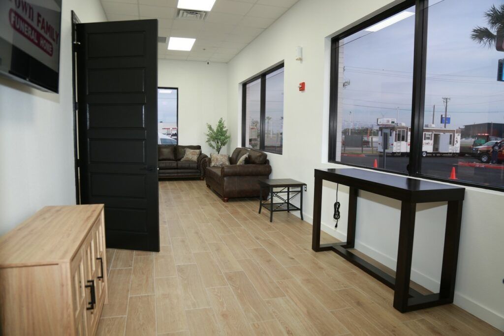 Bright office hallway with wood floors, windows, desks, and a couch near an open door