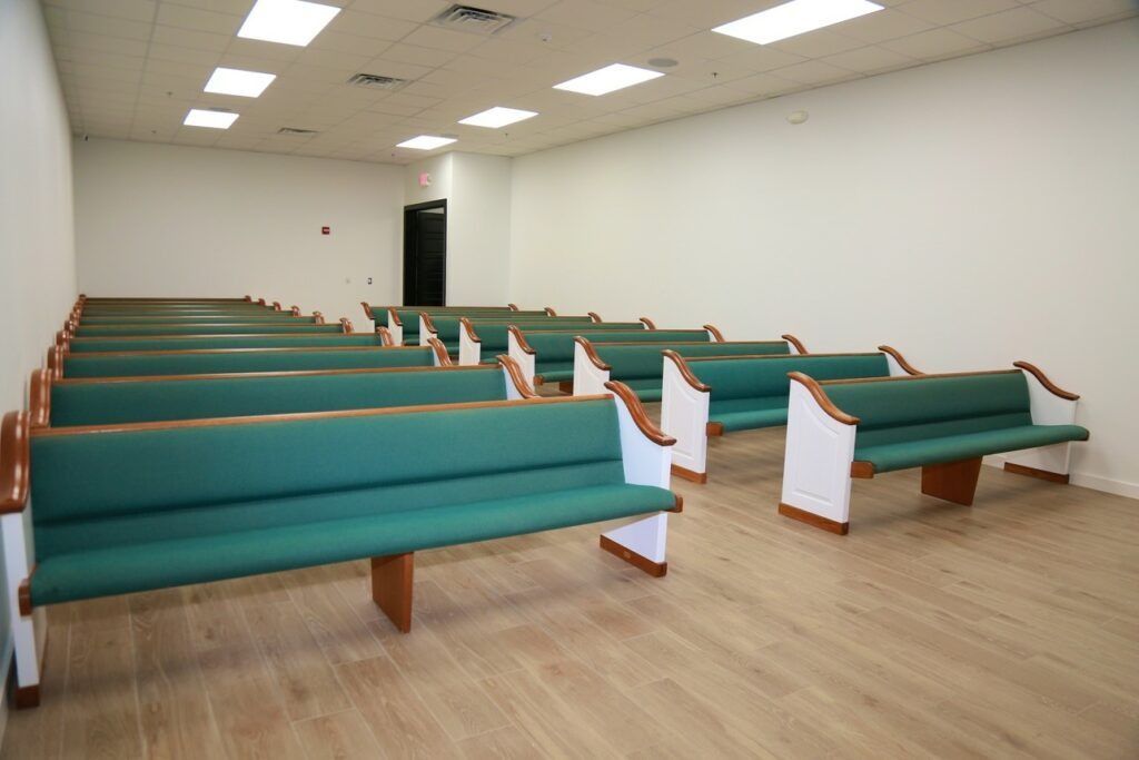 Empty chapel interior with rows of green pews on a light wood floor