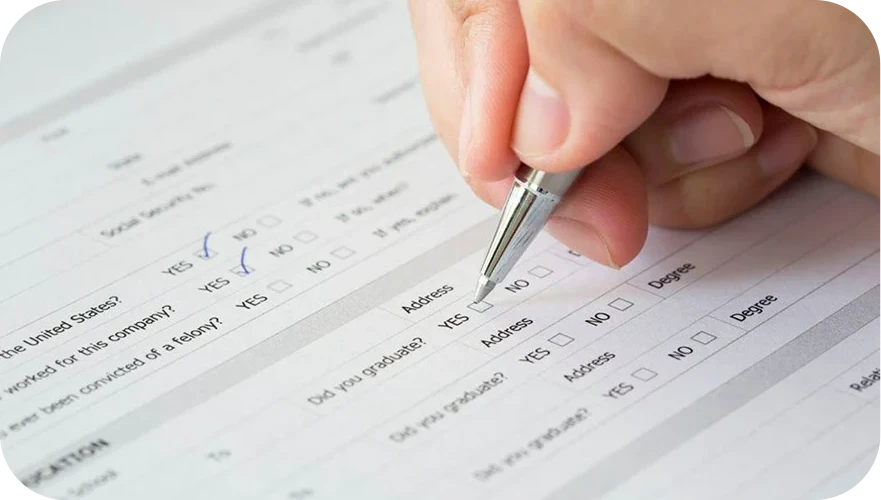 Hand signing a check with a pen on a desk, close-up view of payment form.