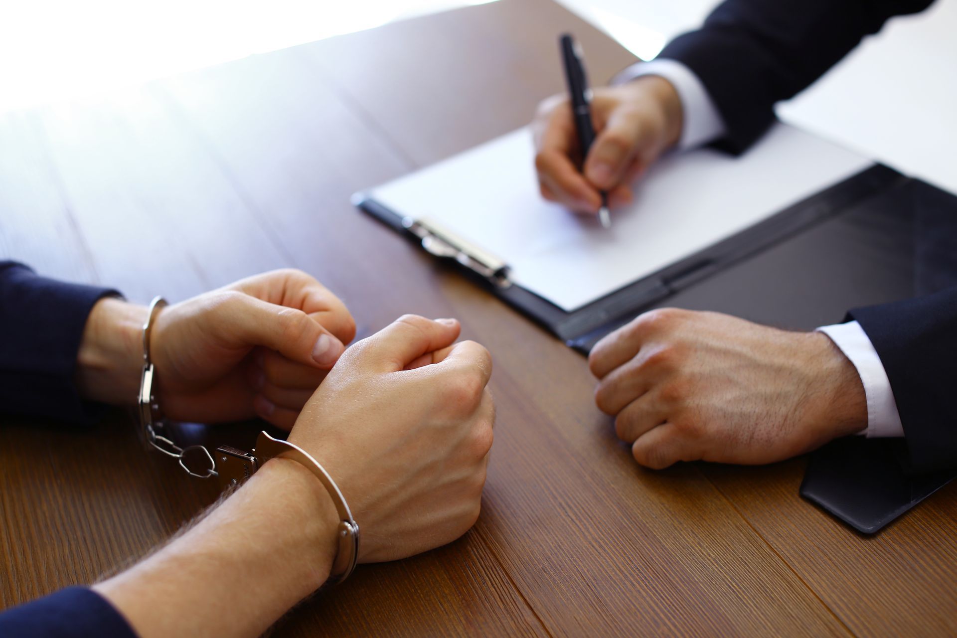 Two people in business attire shaking hands across a desk while another person signs a document
